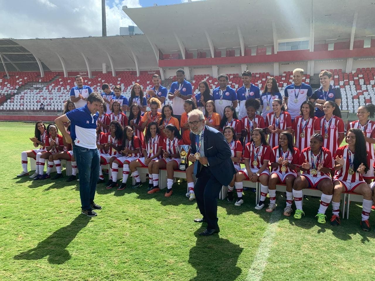 Equipe juvenil de basquete campeã posando com troféu no estádio